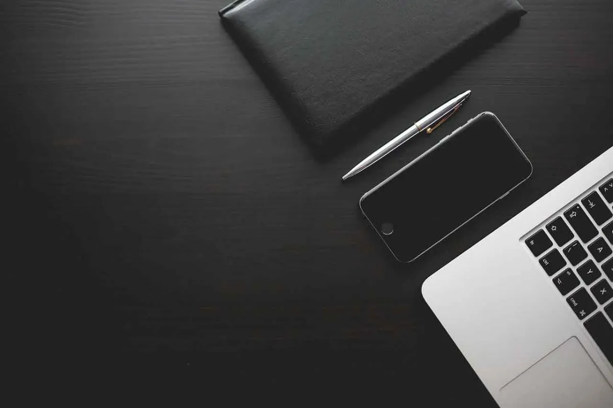 Smartphone, Notizbuch und Laptop auf dunklem Schreibtisch — Mobile First